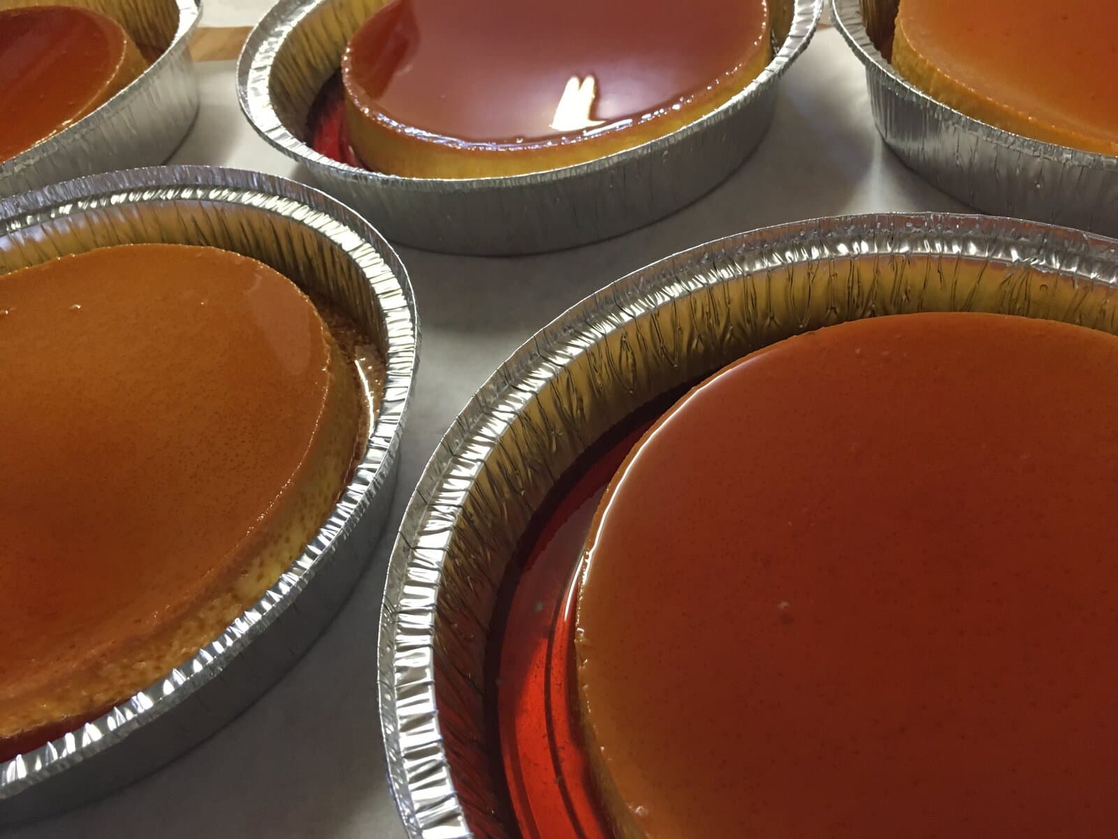 Individual flan napolitano in foil pans with glossy caramel tops at Tlaxcala Bakery