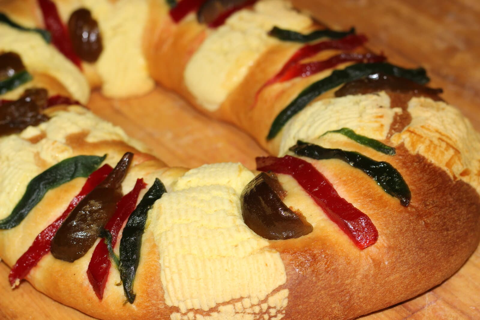 Close-up of a finished Rosca de Reyes with sugar paste and candied fruit on a wooden table